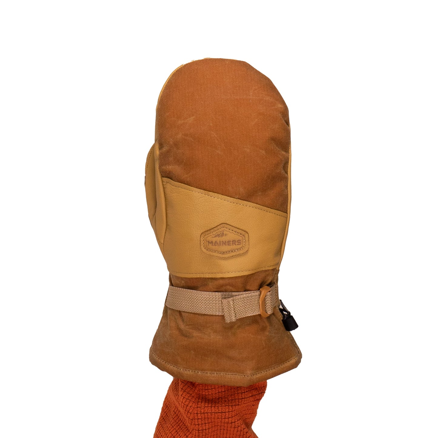 A brown and tan winter mitten by Mainers, known as the Acadia Mitts, is designed from waxed canvas for enhanced warmth and comfort. It includes a buckle strap and showcases the brand's logo on the back, displayed on a person's hand against a plain white background.
