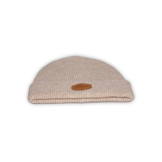 A Mainers Cashmere Beanie in beige with a leather patch.
