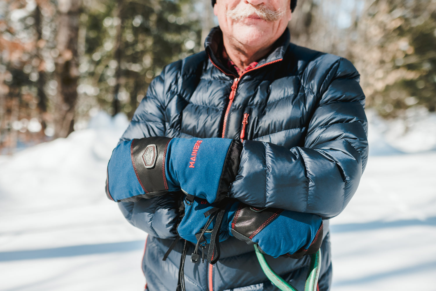 An older man in a blue jacket standing in the snow.