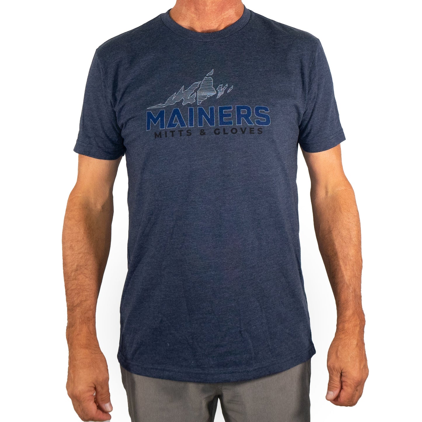 A person wearing a Mainers MG Tee in navy blue, featuring "Mainers Mitts & Gloves" and a mountain design on the front, capturing an adventurous spirit.