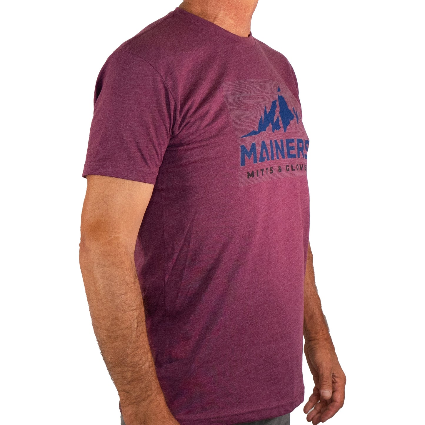 A man stands in a side profile, showcasing his adventurous spirit in a comfortable fit Mainers Ridge Line Tee featuring a mountain logo.