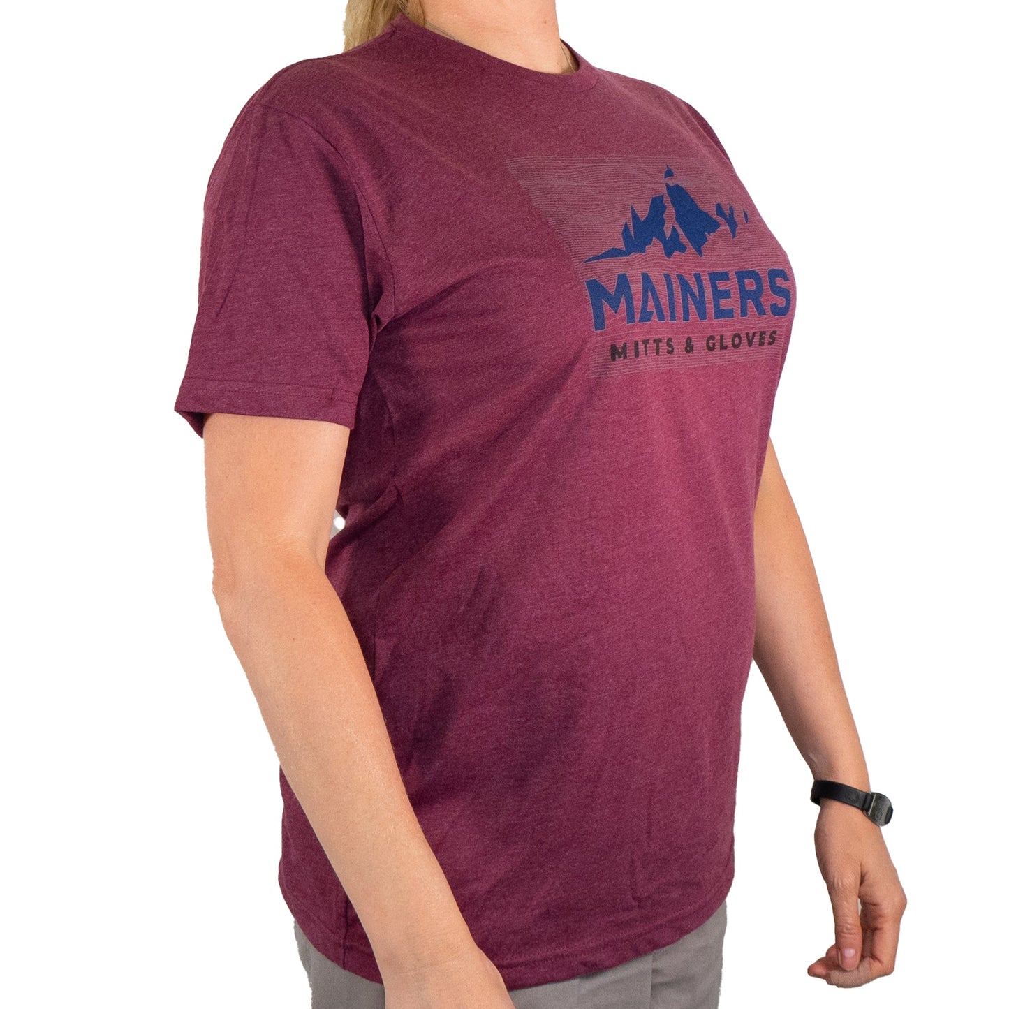 A person wearing a burgundy "Mainers Ridge Line Tee" with mountain graphics exudes an adventurous spirit, embracing the great outdoors with style and a comfortable fit.