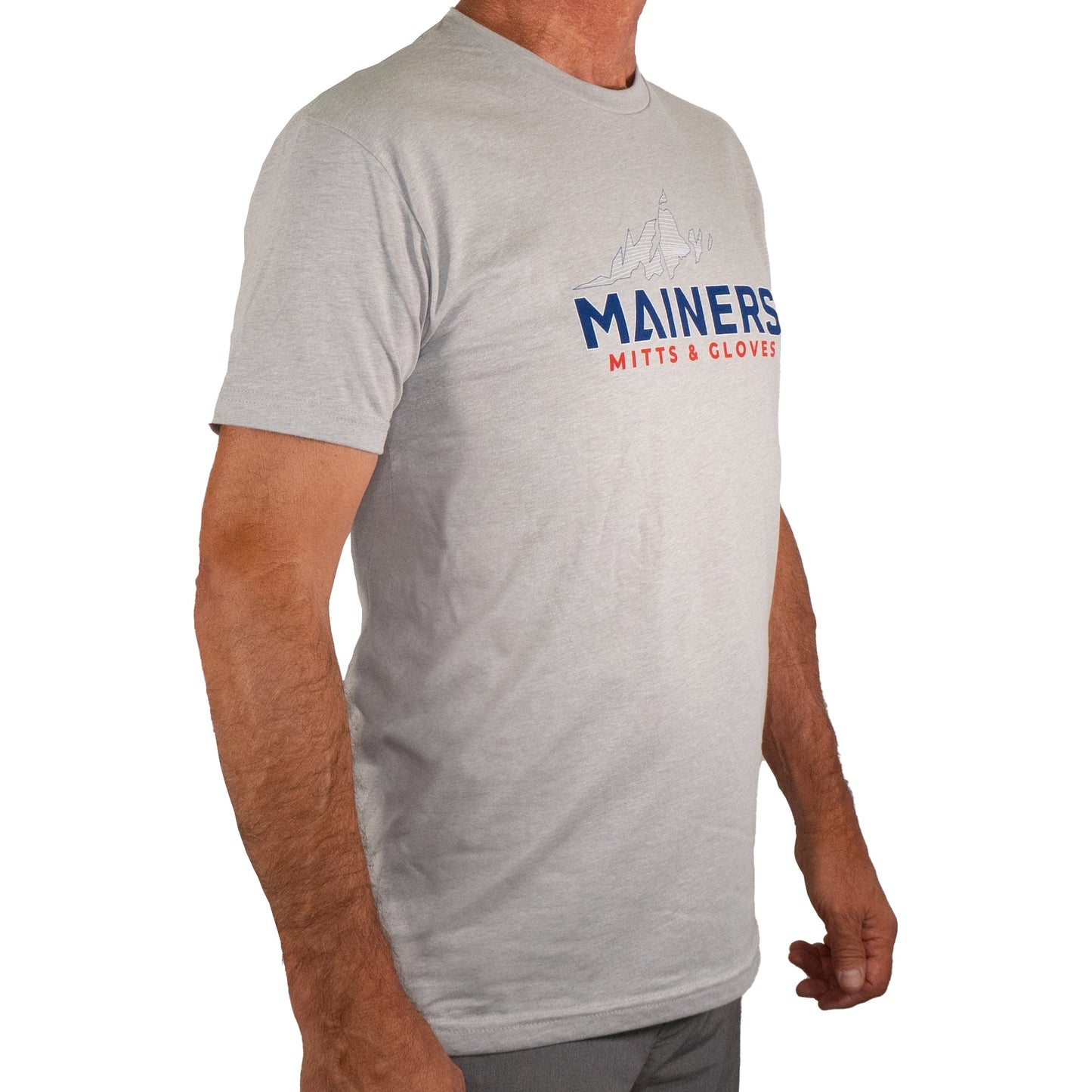Dressed in the premium gray Mainers MG Tee, featuring a bold "Mainers Mitts & Gloves" logo in red and blue, one is perfectly equipped for any outdoor adventure.