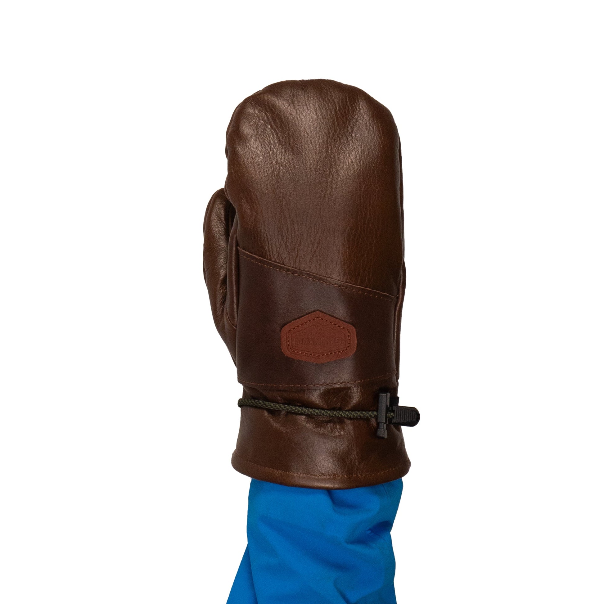 A person with a blue sleeve is wearing a brown mitten made of premium leather, which is equipped with a drawstring. This meticulously crafted piece from Maine showcases the quality of the Portland All-Leather Mitts by Mainers.