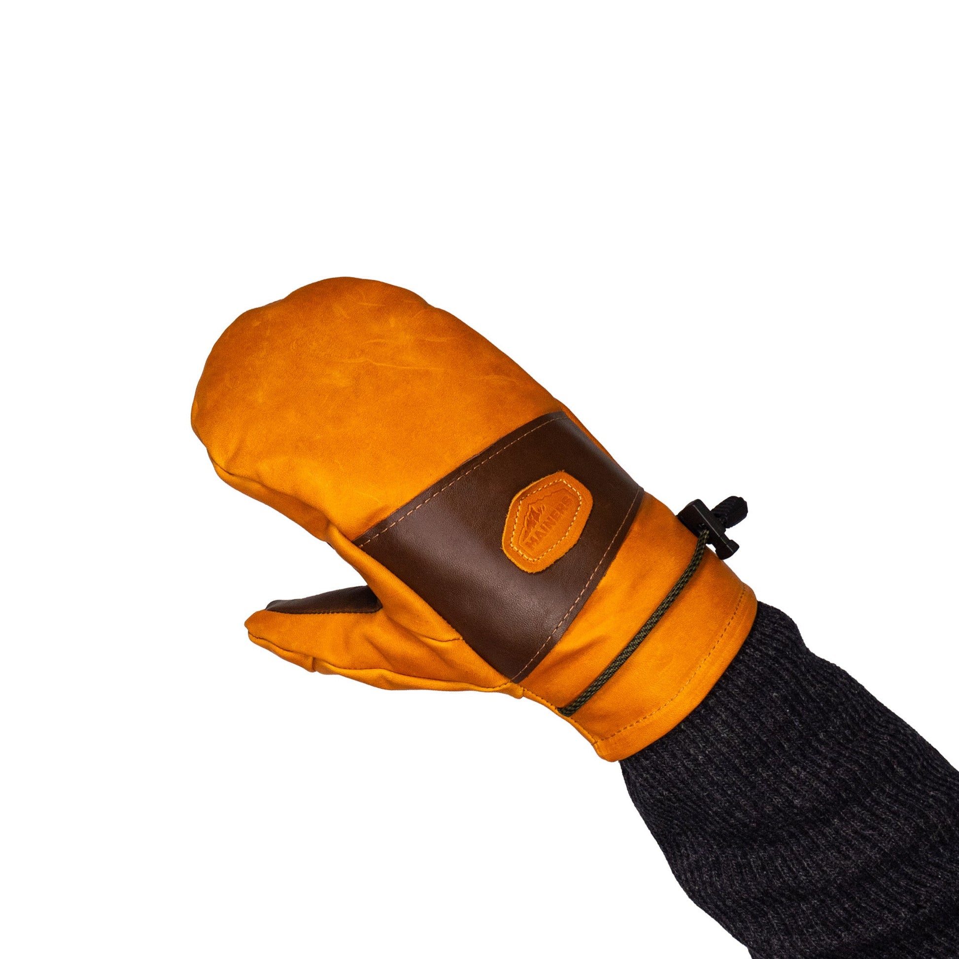 A hand wearing the Portland All-Leather Mitts by Mainers, featuring a wool-pile lining in orange and brown with a black cuff, is raised against a stark white background, highlighting its Maine craftsmanship.