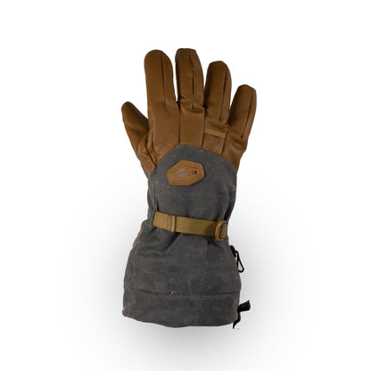 The Bethel Glove by Mainers is a single insulated glove in brown and gray, designed for cold weather adventures. It features a strap and patch on the back, while its waxed canvas construction boosts outdoor performance, guaranteeing warmth and durability in harsh conditions.