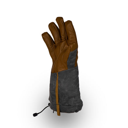 The Bethel Glove by Mainers, made from brown and gray leather, is displayed standing upright on a white background. It includes an adjustable wrist strap designed for superior outdoor performance.