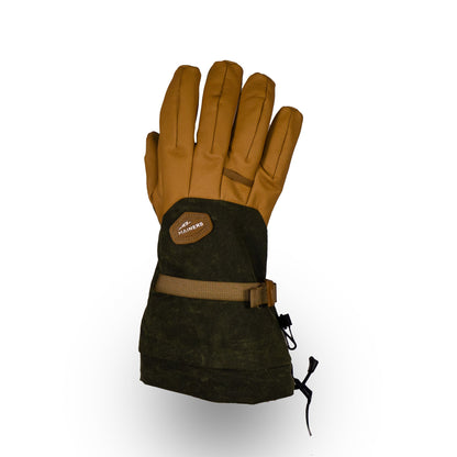 The Mainers Bethel Glove, engineered for outdoor excellence, boasts a brown and green waxed canvas exterior paired with an insulated interior and is enhanced by a durable buckle and strap. Displayed against a simple white background, its robust elegance stands out.