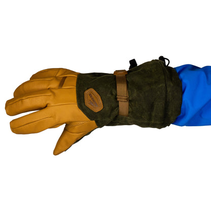 The Mainers Bethel Glove, made with brown leather and green fabric, features a waxed canvas strap designed for improved outdoor performance, making it a perfect match for a blue sleeve.