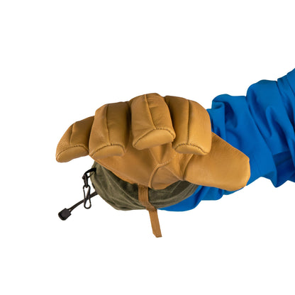 A hand in a blue sleeve, adorned with a Mainers Bethel Glove, holds a green pouch with a small black buckle, ideal for outdoor performance.