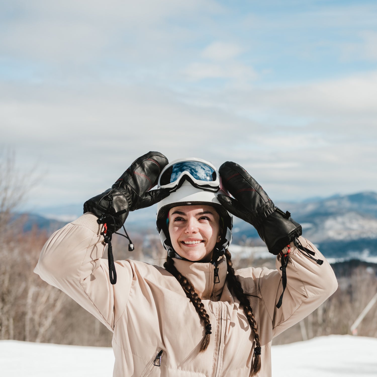 A woman wearing ski goggles and Mainers All-Leather Mitts on a snowy mountain.