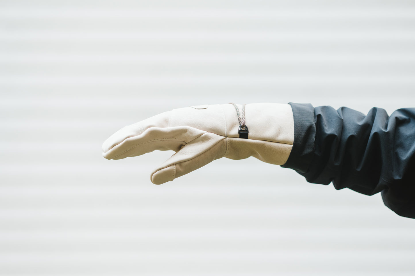 A person is holding a Mainers Caribou Mitts glove in front of a white wall.