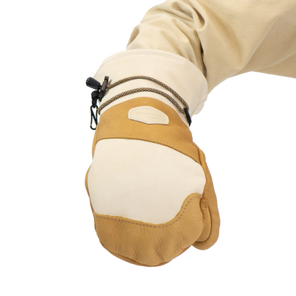 Beige and brown mitten worn by a person on a white background