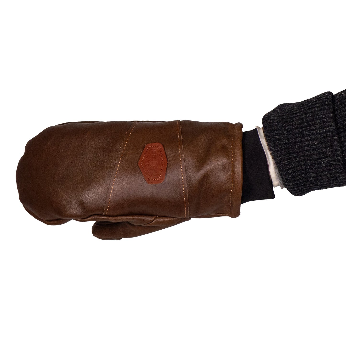 A person wearing a dark knitted sleeve is sporting the Peaks All-Leather Mitts by Mainers, crafted from premium brown leather with a small patch on top, ideal for cold-weather adventures.