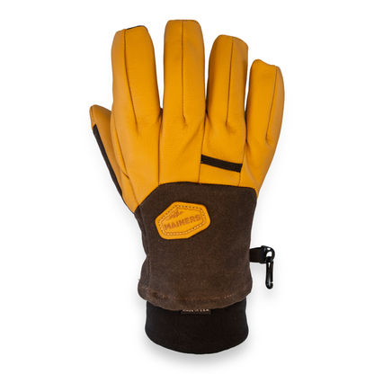 A single heavy-duty glove shown from the back, featuring a leather back, a brown waxed canvas wrist panel, and a black fleece cuff. A leather brand patch on the wrist reads 'MAINERS'.