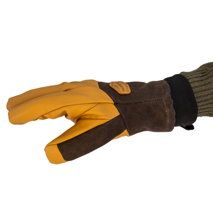 A single glove shown on a hand, featuring a  leather back and fingers, dark brown waxed canvas palm and wrist, and a black cuff, with a ribbed olive green knit sleeve visible.