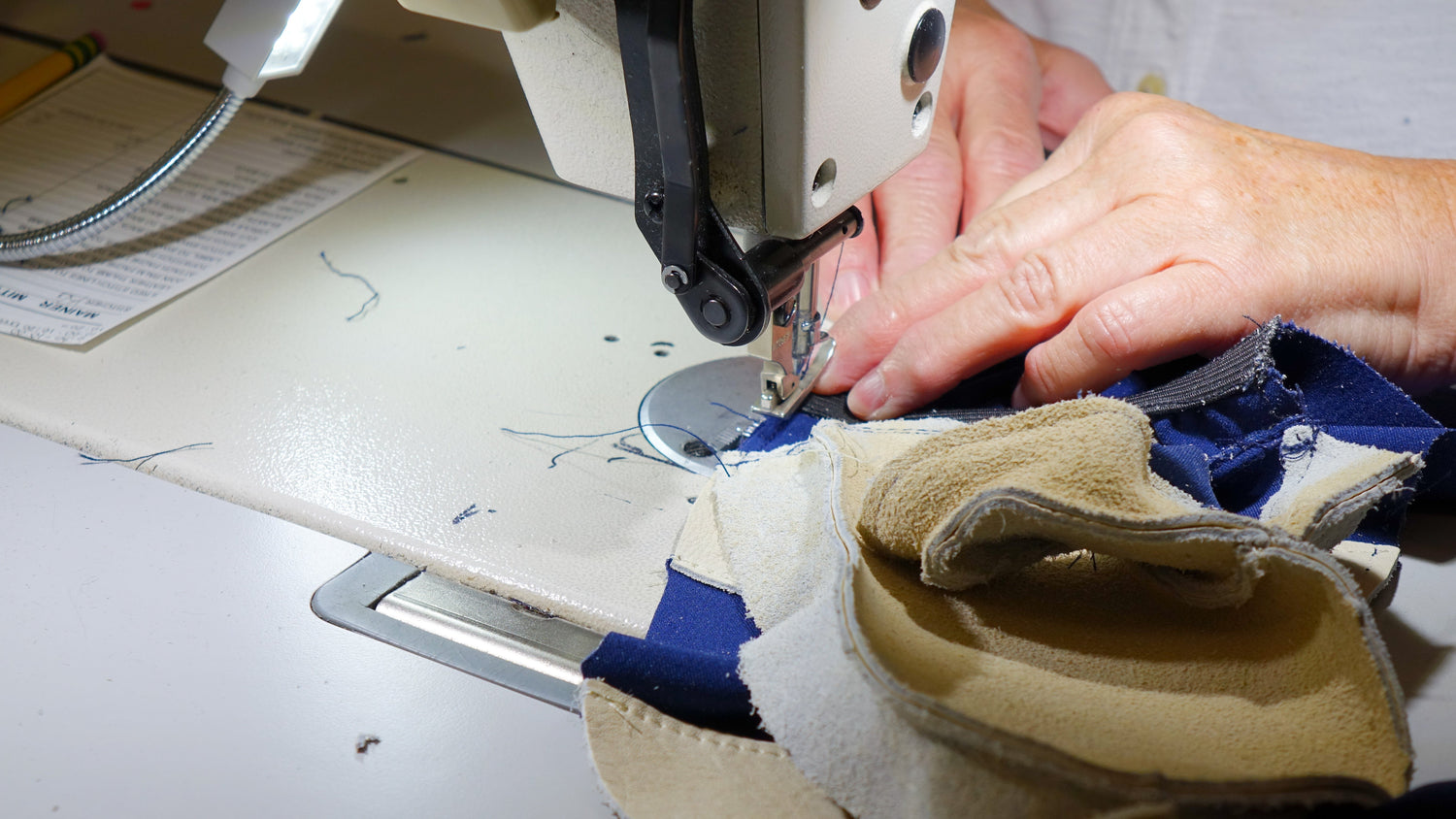 A person using a sewing machine to sew a piece of fabric.